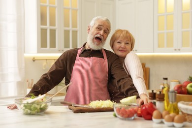 Photo of Senior couple cooking together at table in kitchen