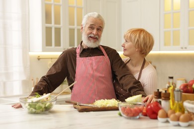 Photo of Senior couple cooking together at table in kitchen