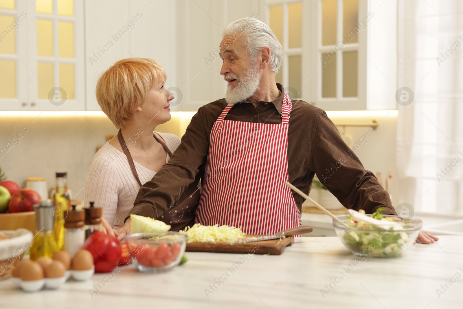 Photo of Senior couple cooking together at table in kitchen