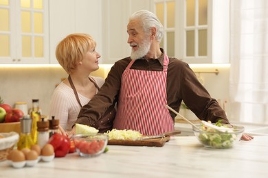 Senior couple cooking together at table in kitchen