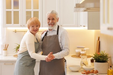 Photo of Senior couple dancing while cooking in kitchen