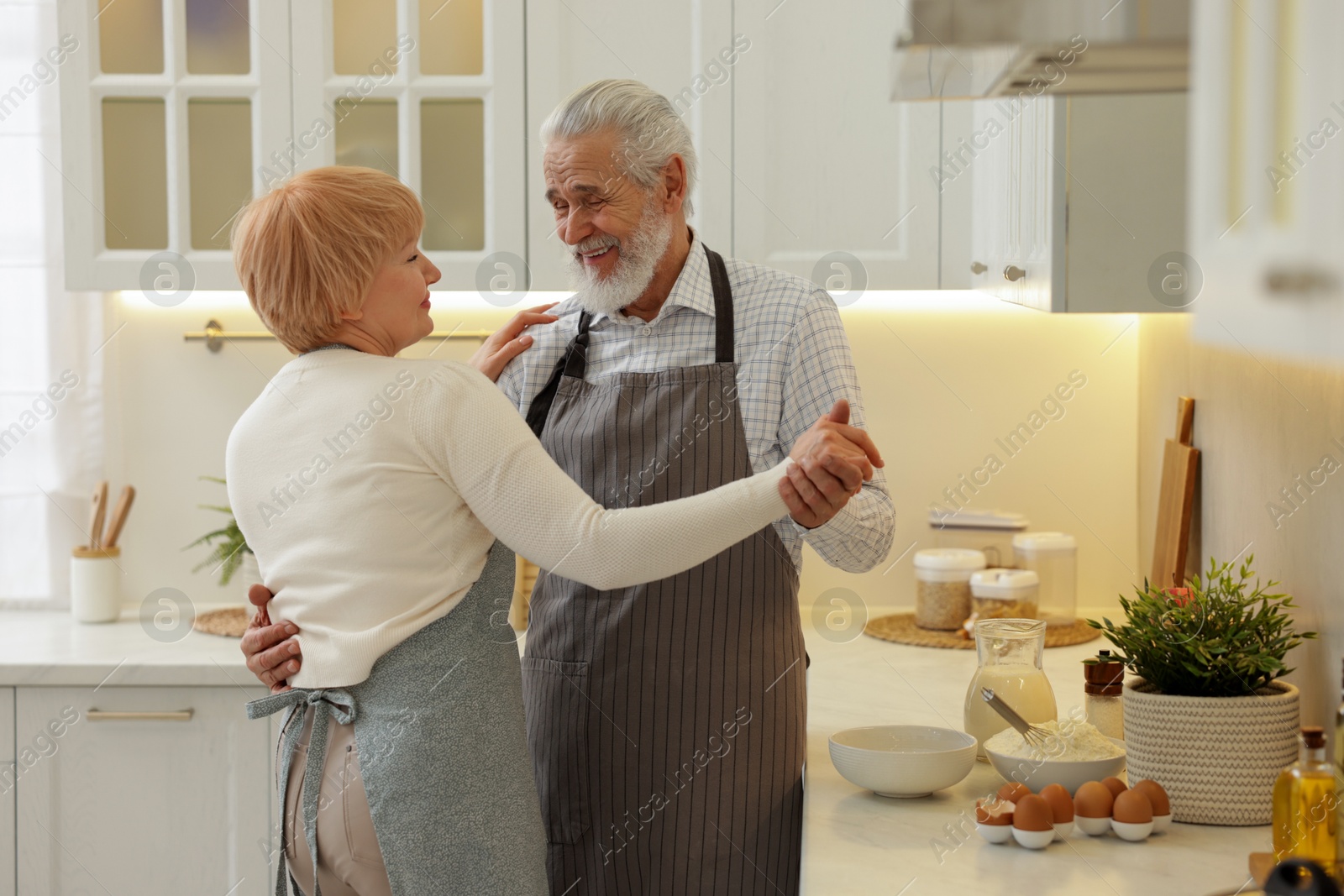 Photo of Senior couple dancing while cooking in kitchen