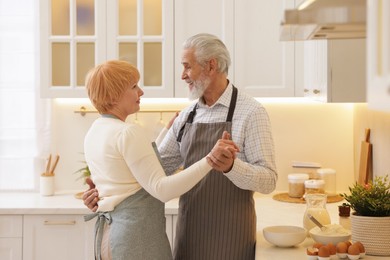 Photo of Senior couple dancing while cooking in kitchen