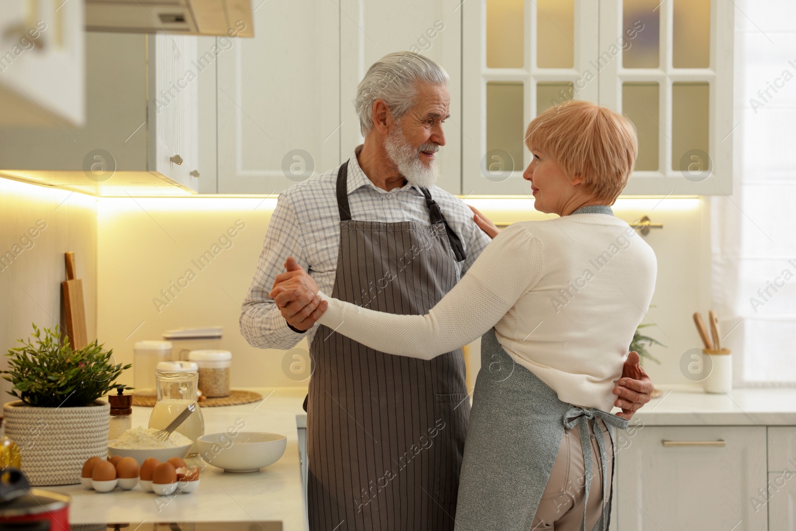 Photo of Senior couple dancing while cooking in kitchen