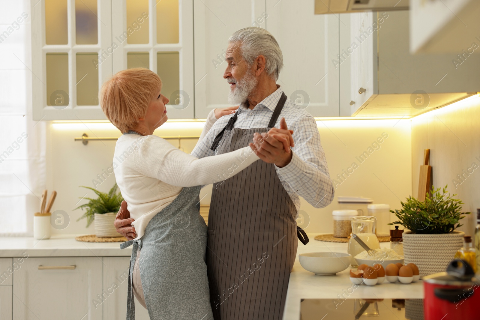 Photo of Senior couple dancing while cooking in kitchen