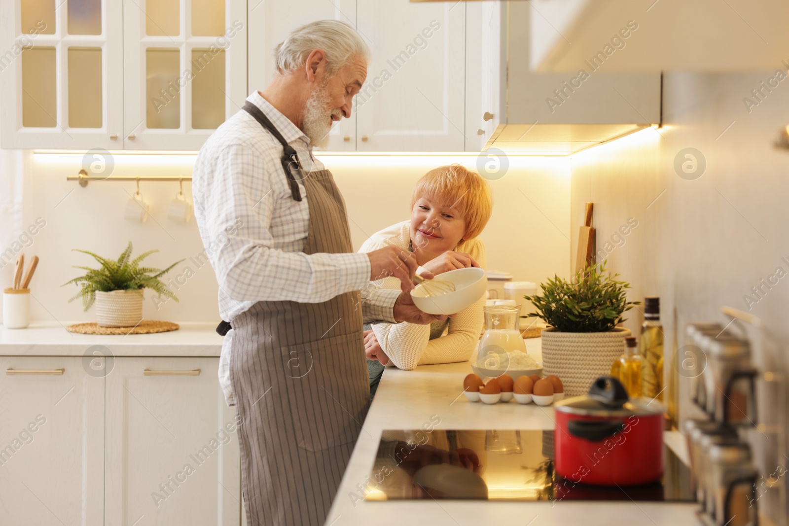 Photo of Senior couple cooking together at counter in kitchen