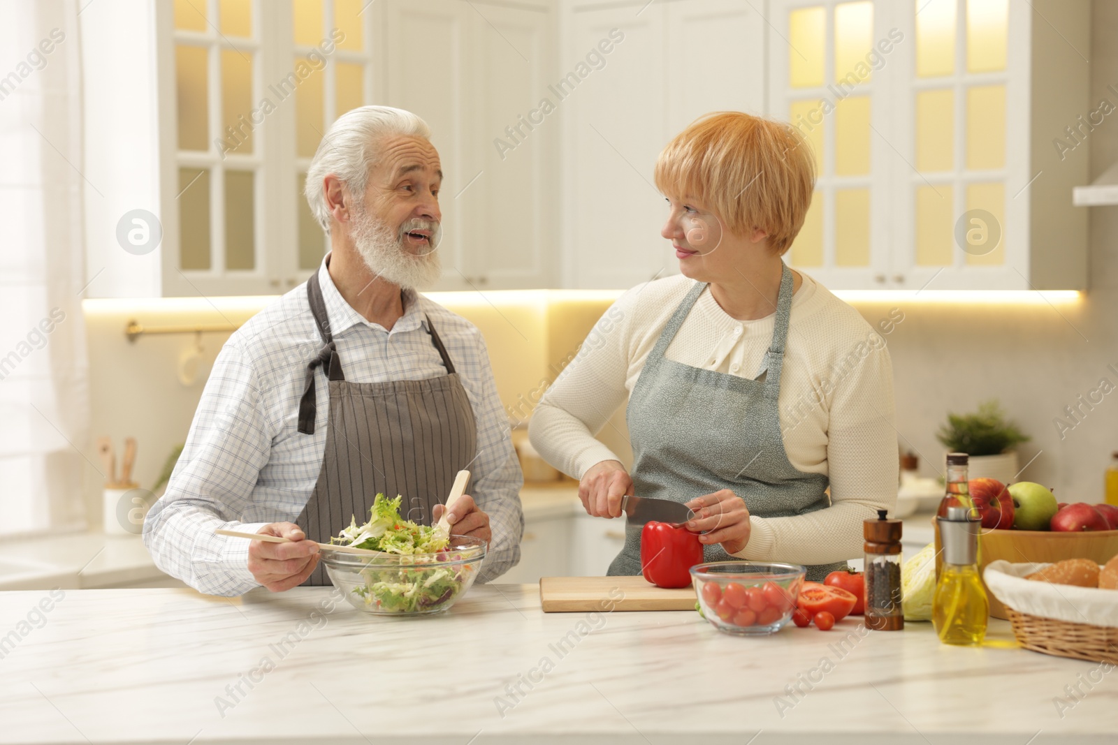 Photo of Senior couple cooking together at table in kitchen