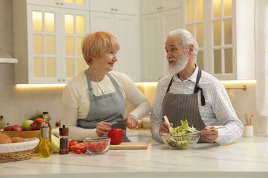 Photo of Senior couple cooking together at table in kitchen