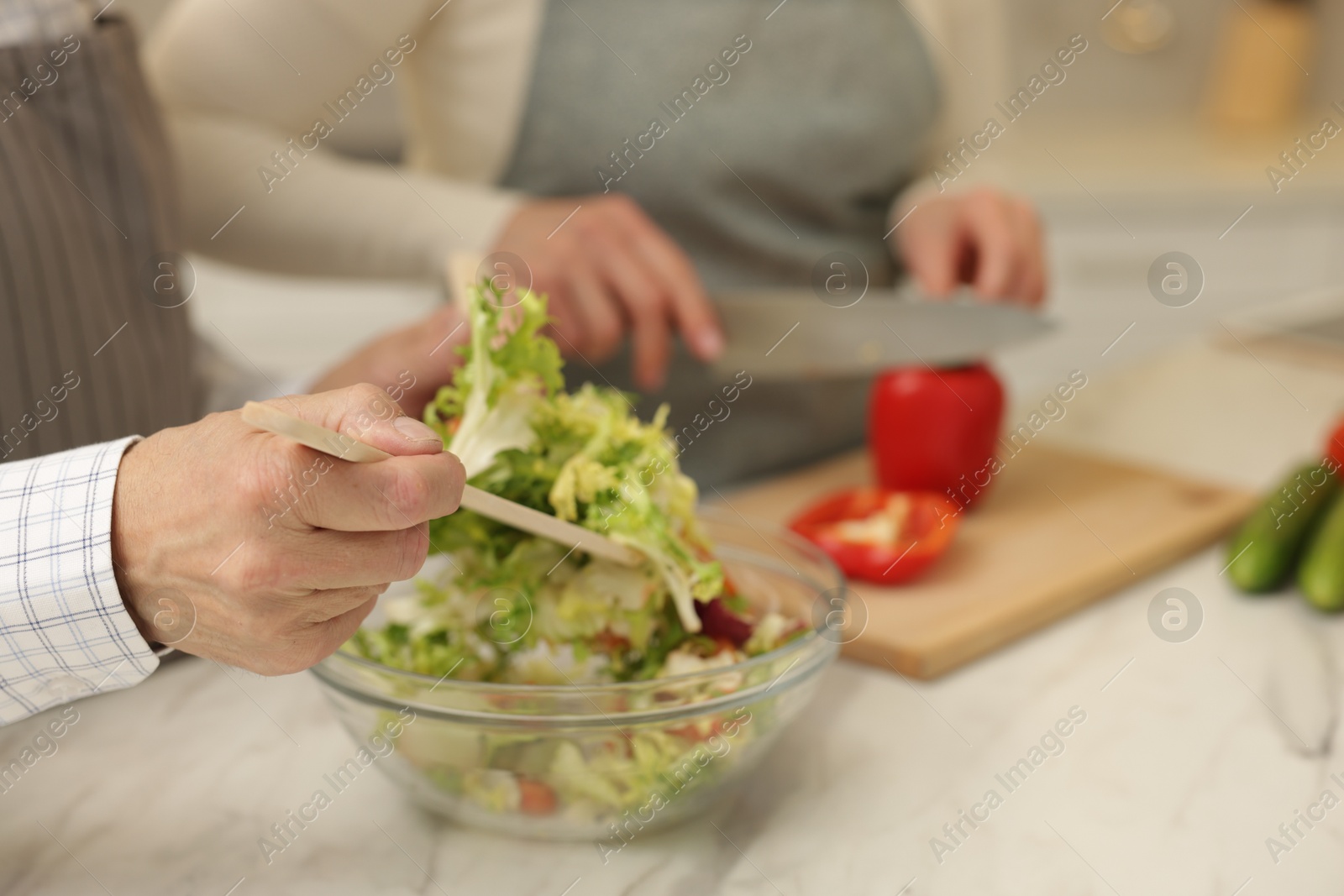 Photo of Senior couple cooking together at table in kitchen, closeup