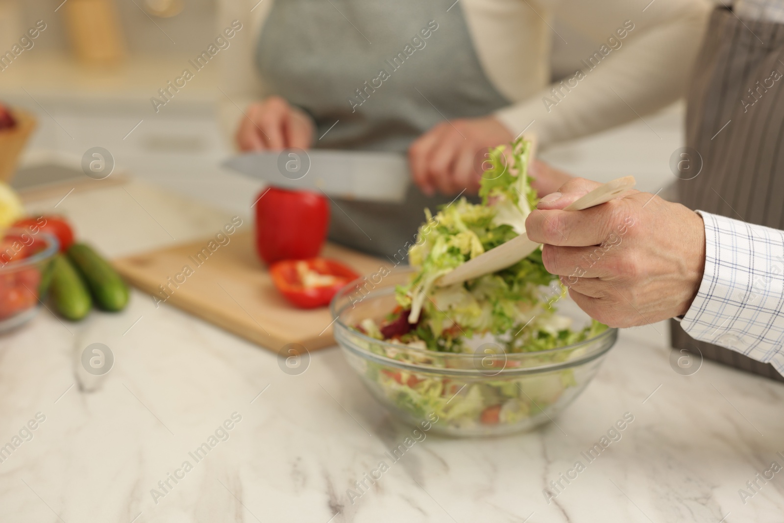 Photo of Senior couple cooking together at table in kitchen, closeup