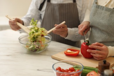 Photo of Senior couple cooking together at table in kitchen, closeup