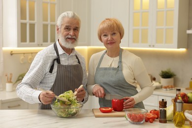 Photo of Senior couple cooking together at table in kitchen