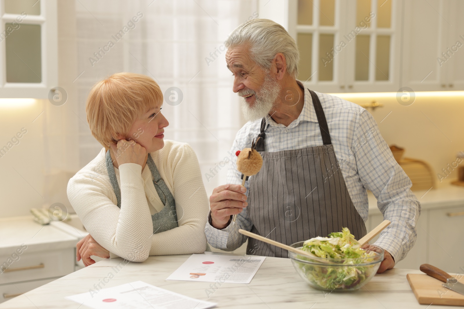 Photo of Senior couple cooking together at table in kitchen