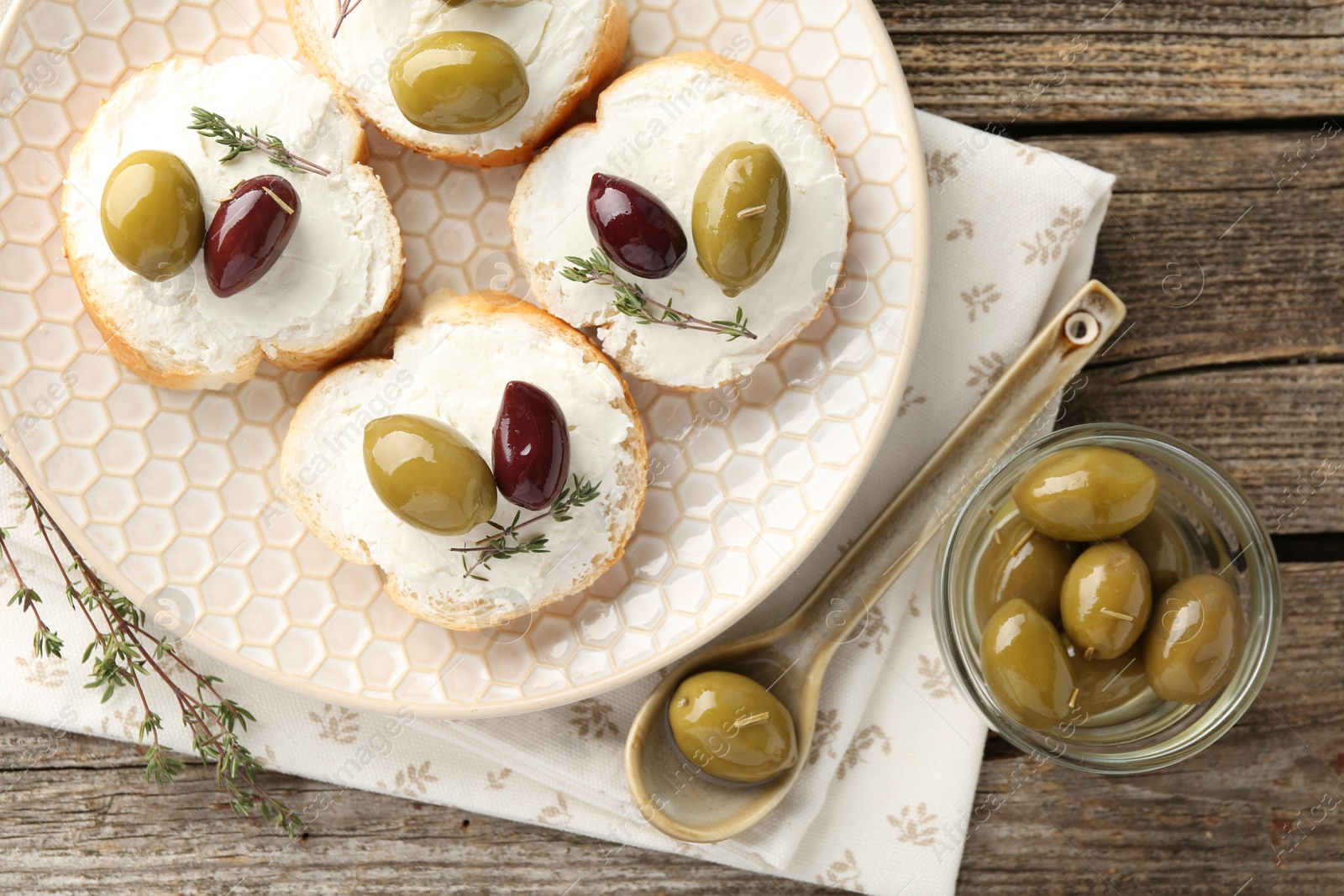 Photo of Delicious sandwiches with marinated olives, cream cheese and thyme on wooden table, flat lay