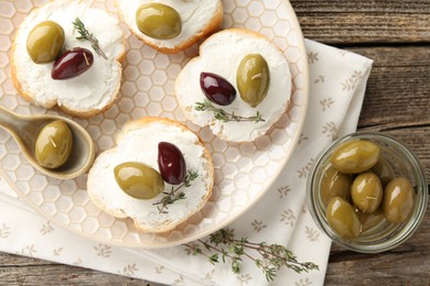 Photo of Delicious sandwiches with marinated olives, cream cheese and thyme on wooden table, flat lay