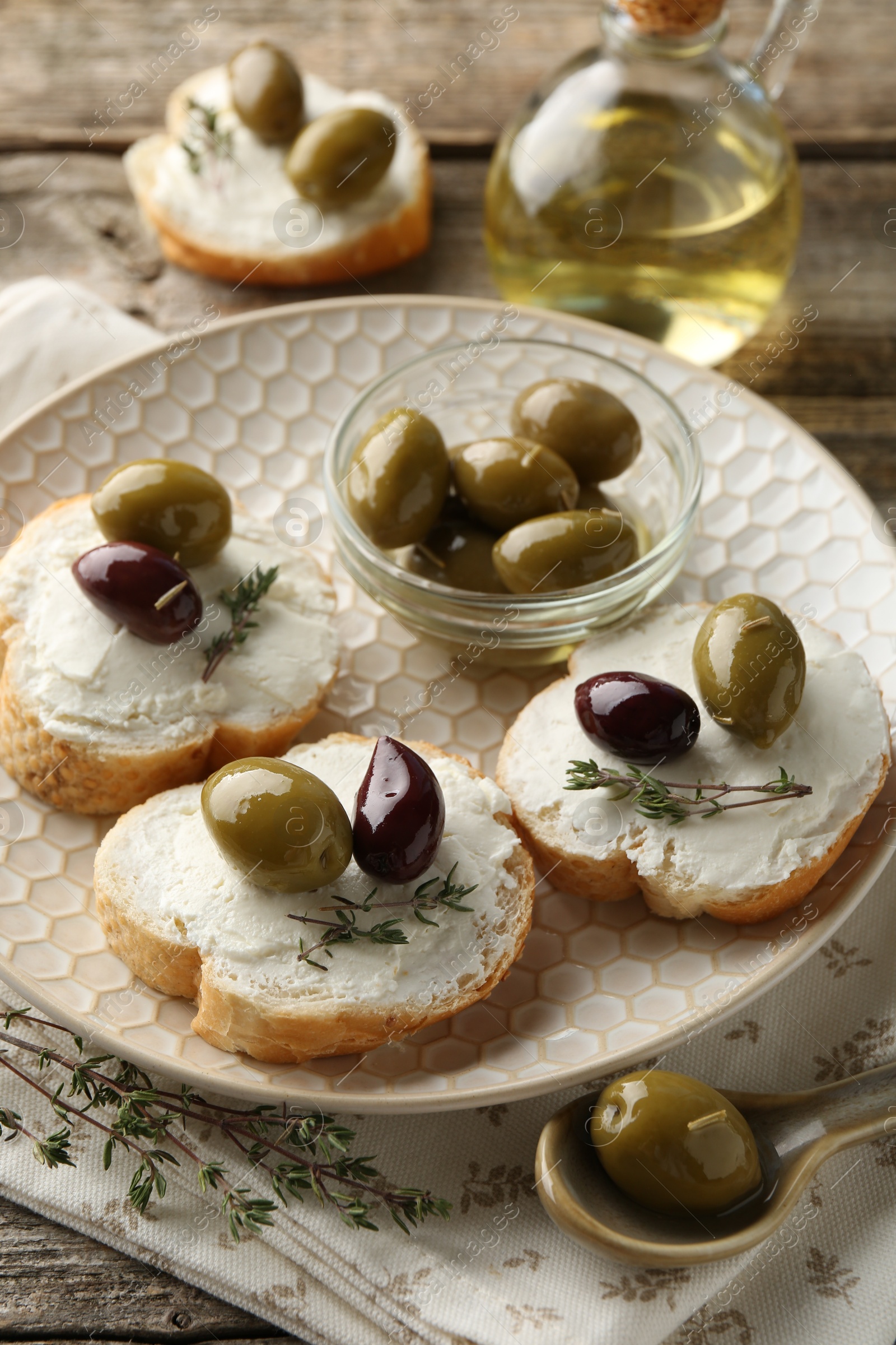 Photo of Delicious sandwiches with marinated olives, cream cheese and thyme on wooden table, closeup