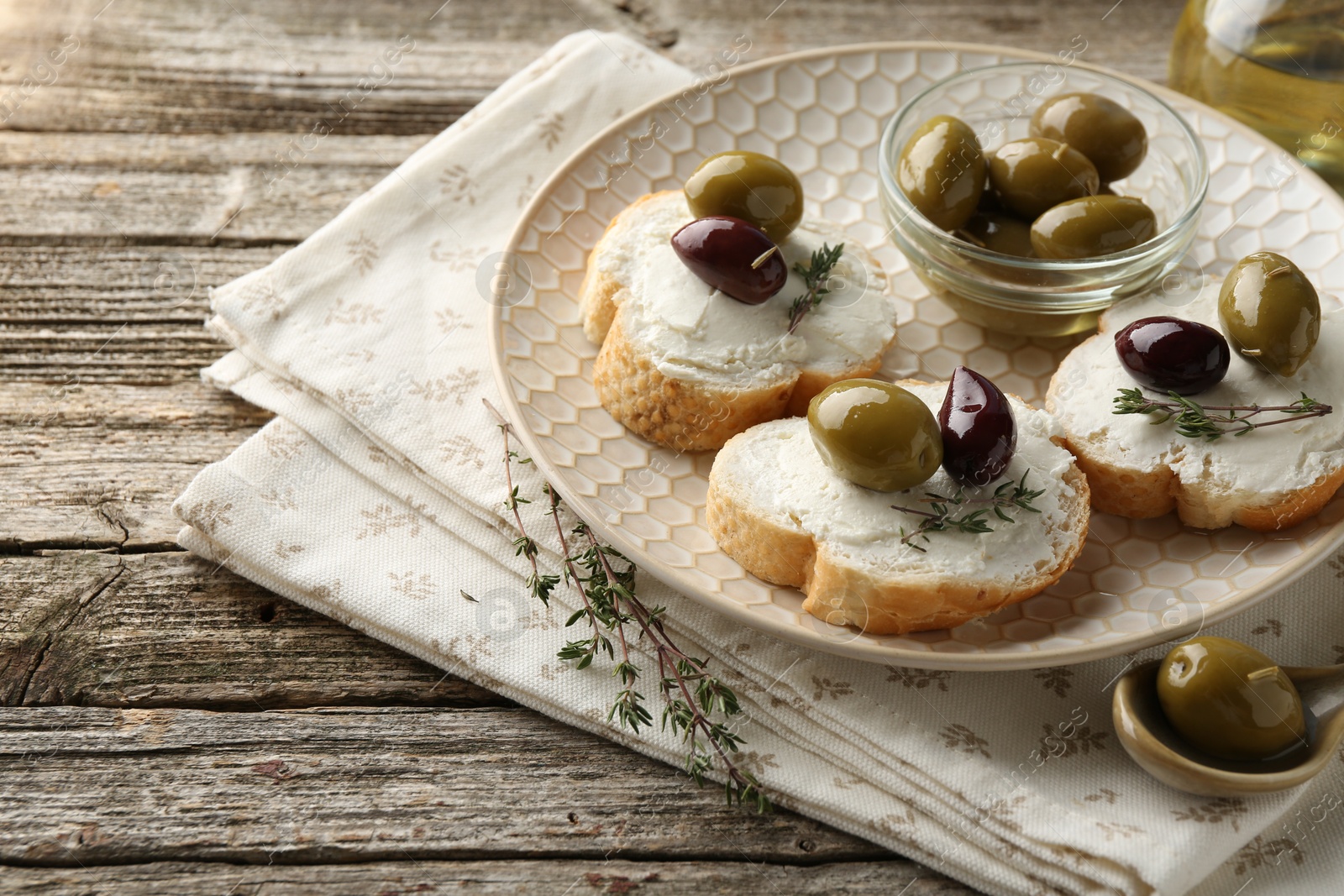 Photo of Delicious sandwiches with marinated olives, cream cheese and thyme on wooden table, closeup. Space for text