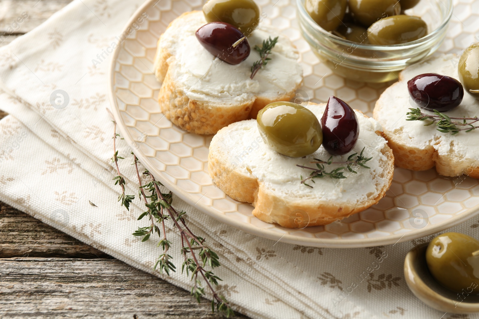 Photo of Delicious sandwiches with marinated olives, cream cheese and thyme on wooden table, closeup