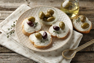 Photo of Delicious sandwiches with marinated olives, cream cheese and thyme on wooden table, closeup