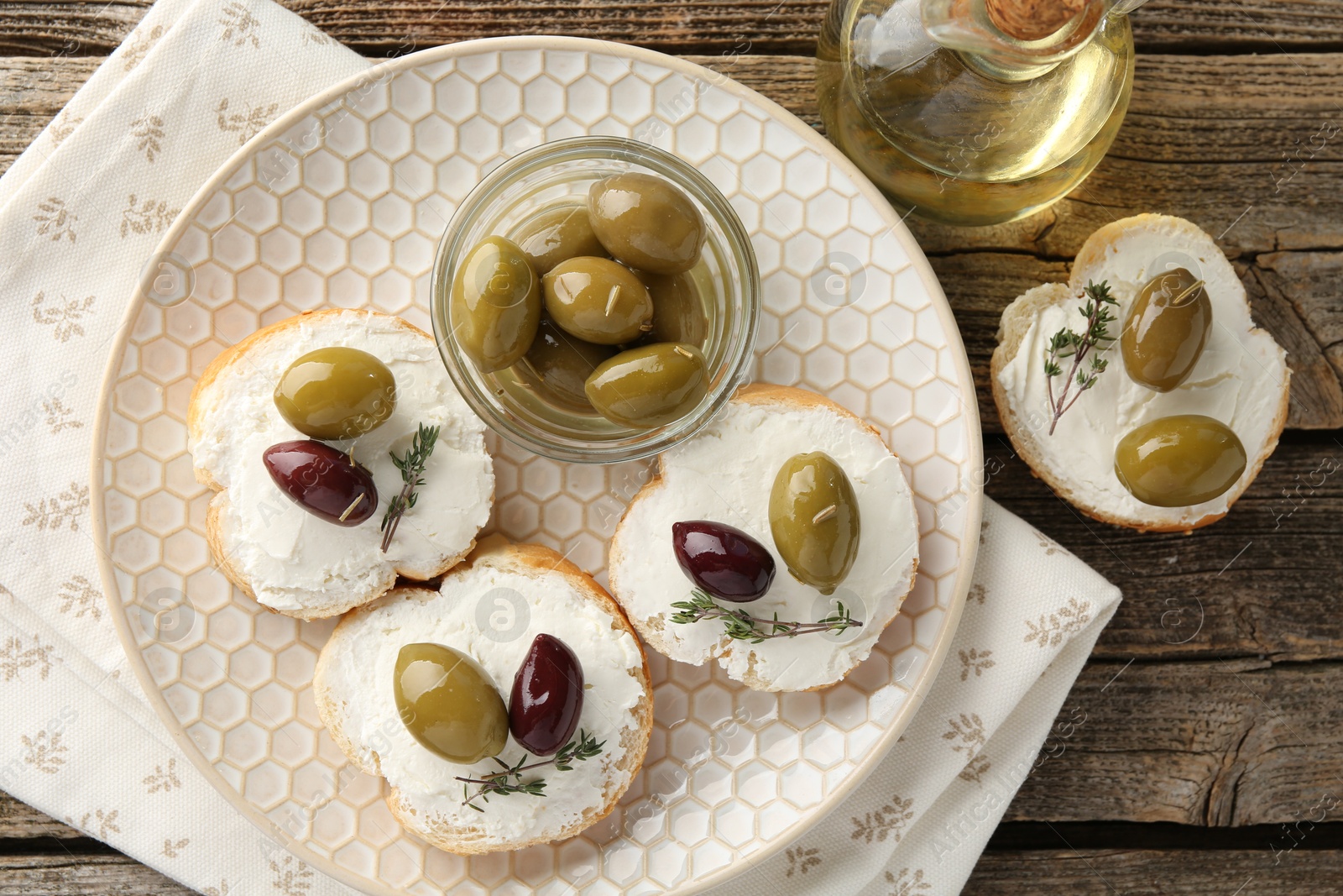 Photo of Delicious sandwiches with marinated olives, cream cheese and thyme on wooden table, flat lay