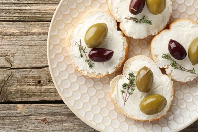 Photo of Delicious sandwiches with marinated olives, cream cheese and thyme on wooden table, top view. Space for text