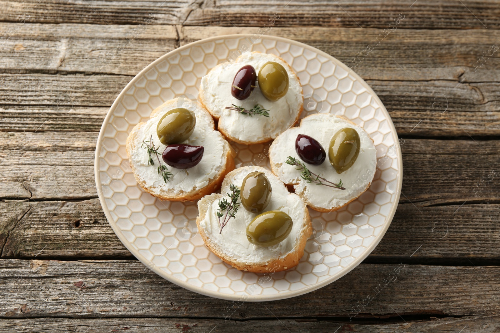 Photo of Delicious sandwiches with marinated olives, cream cheese and thyme on wooden table, top view