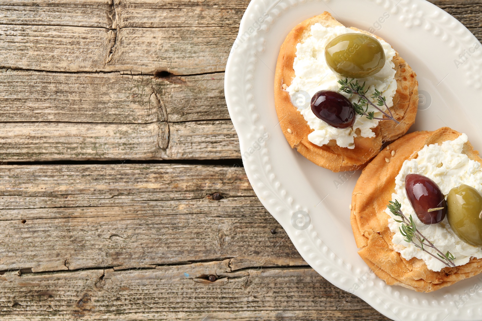 Photo of Delicious sandwiches with marinated olives, cream cheese and thyme on wooden table, top view. Space for text