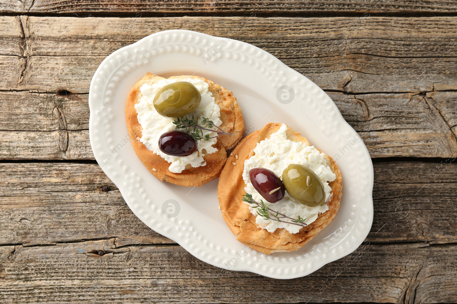 Photo of Delicious sandwiches with marinated olives, cream cheese and thyme on wooden table, top view