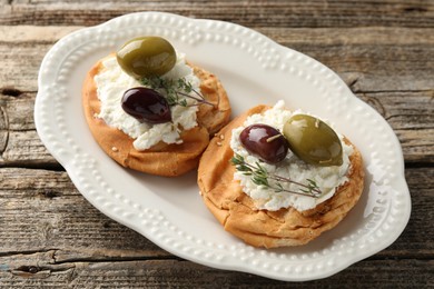 Photo of Delicious sandwiches with marinated olives, cream cheese and thyme on wooden table, above view