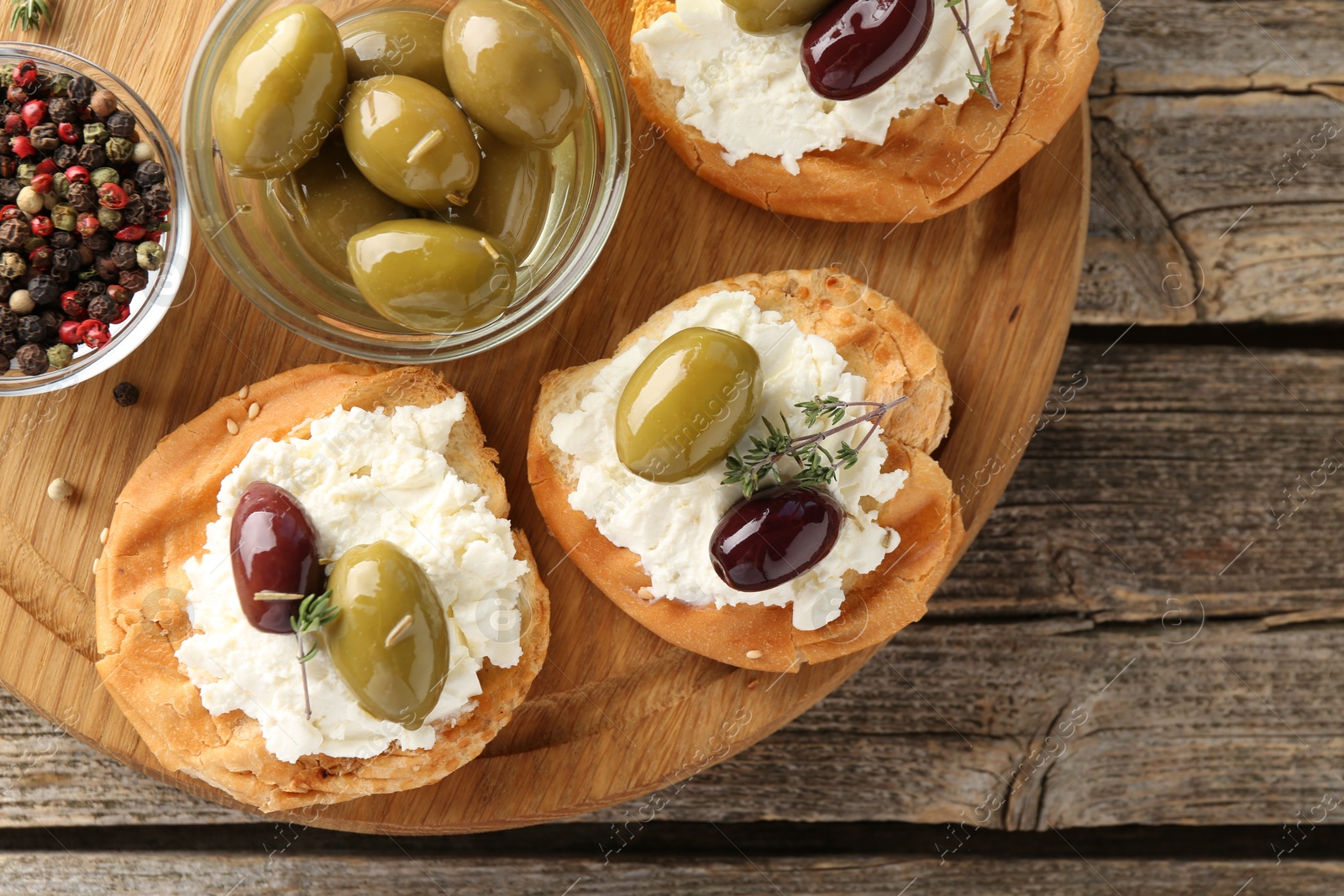 Photo of Delicious sandwiches with marinated olives, cream cheese and thyme on wooden table, top view