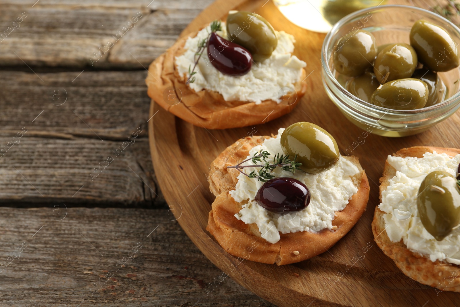 Photo of Delicious sandwiches with marinated olives, cream cheese and thyme on wooden table, closeup. Space for text