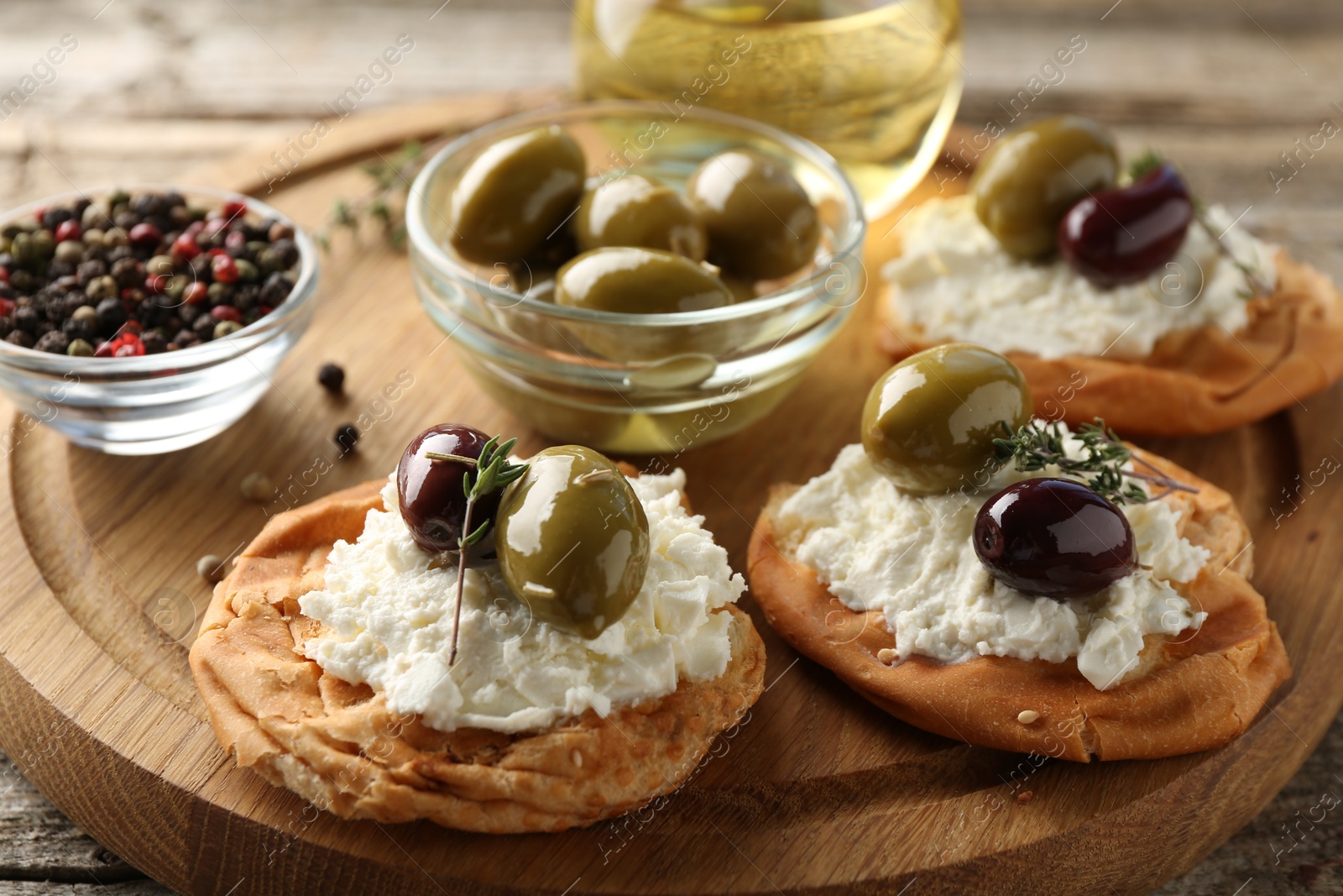 Photo of Delicious sandwiches with marinated olives, cream cheese and thyme on wooden table, closeup