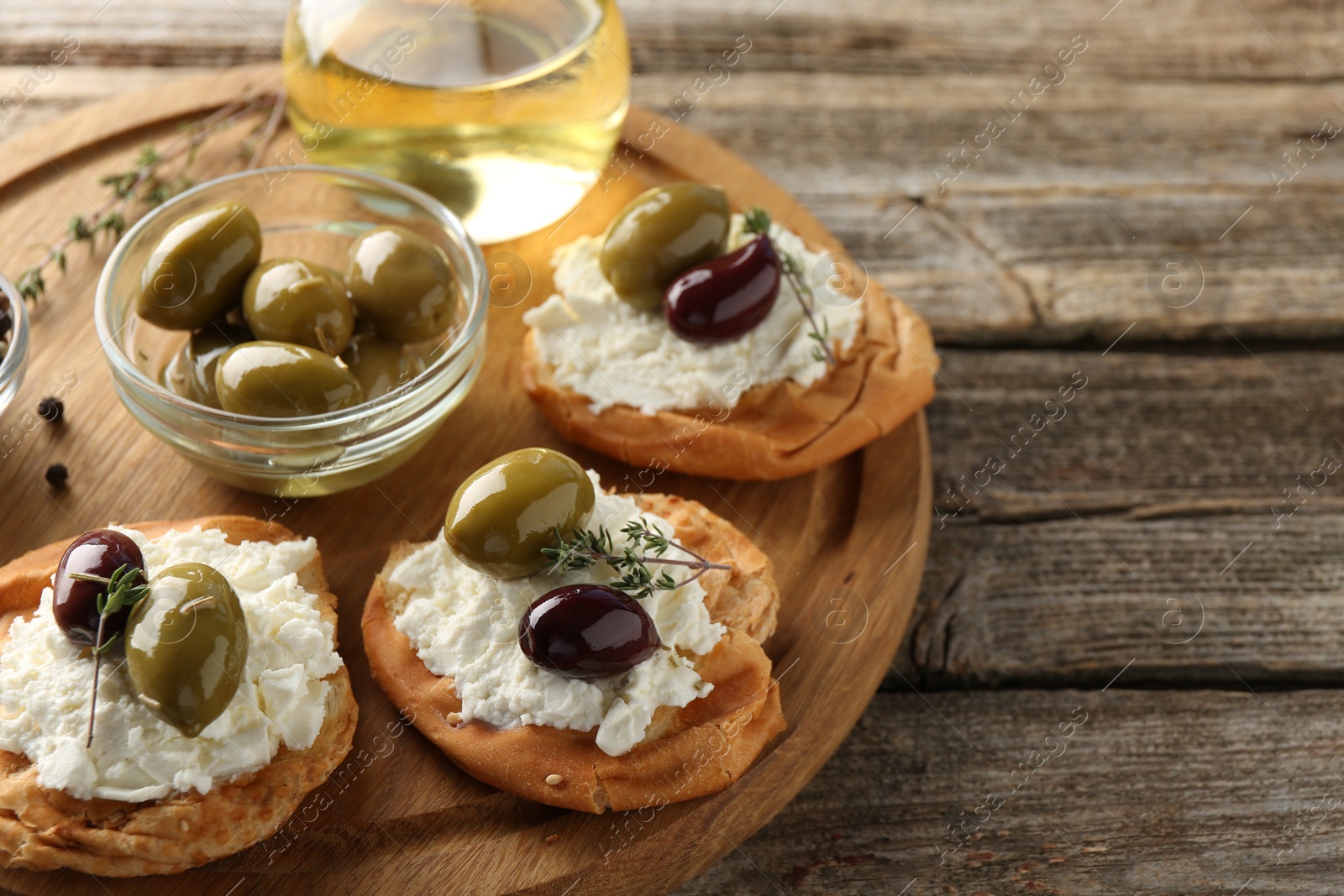 Photo of Delicious sandwiches with marinated olives, cream cheese and thyme on wooden table, closeup. Space for text