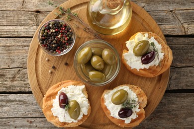 Photo of Delicious sandwiches with marinated olives, cream cheese and thyme on wooden table, top view