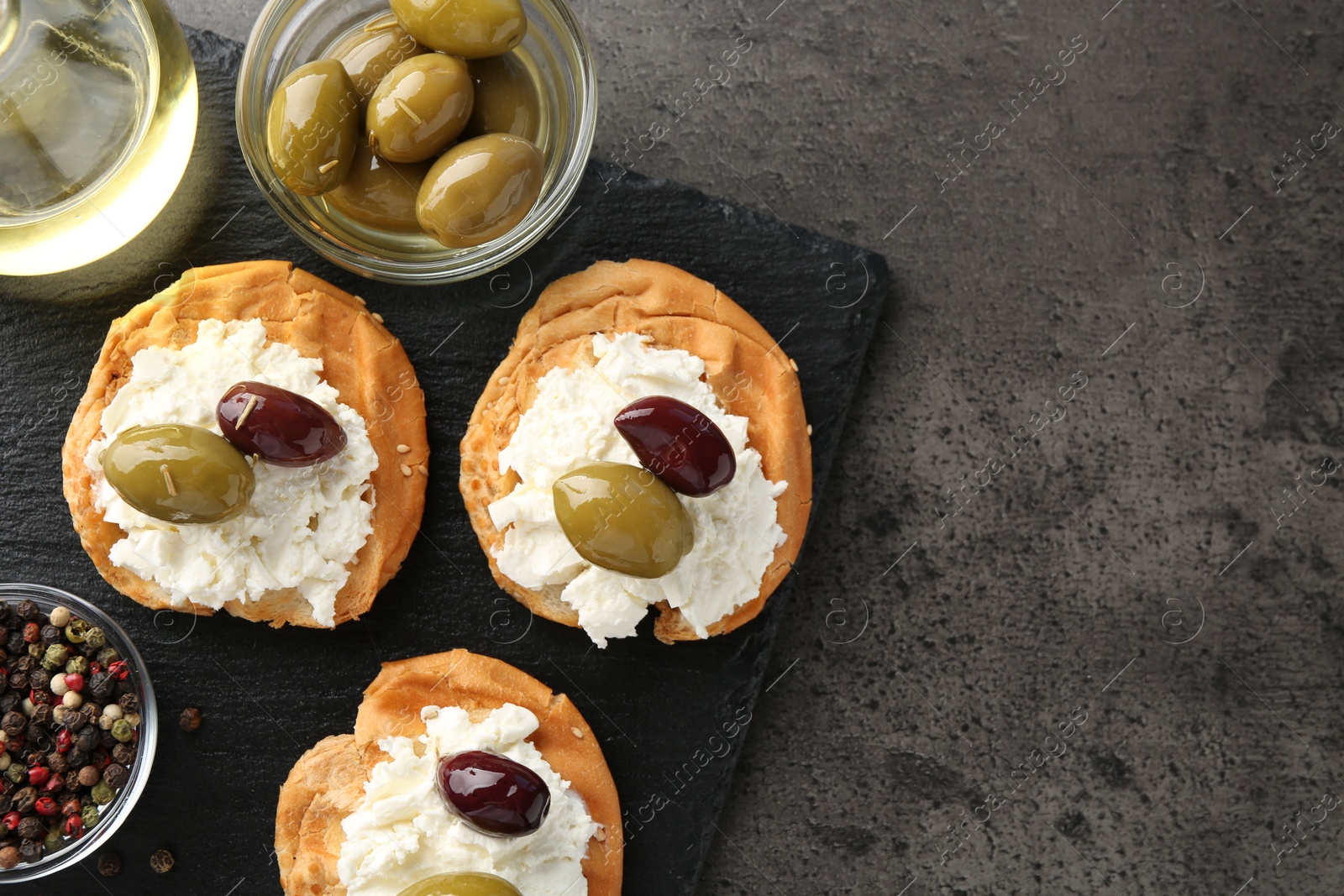 Photo of Delicious sandwiches with marinated olives, cream cheese and peppercorns on dark textured table, top view. Space for text