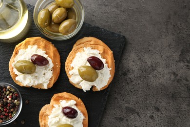 Photo of Delicious sandwiches with marinated olives, cream cheese and peppercorns on dark textured table, top view. Space for text