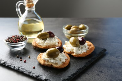 Photo of Delicious sandwiches with marinated olives, cream cheese and peppercorns on dark textured table, closeup