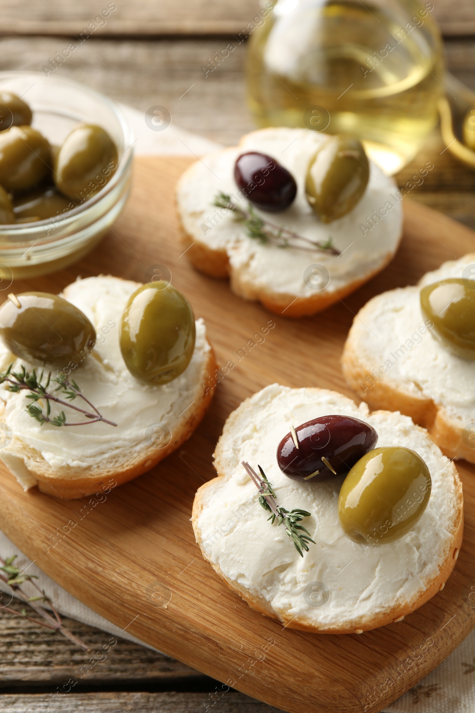 Photo of Delicious sandwiches with marinated olives, cream cheese and thyme on wooden table, closeup