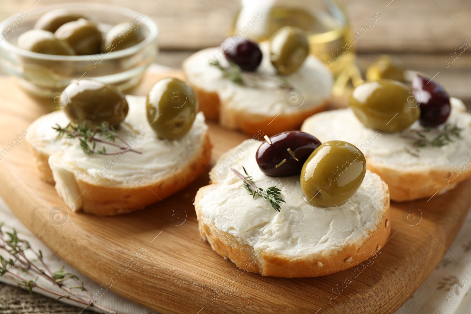 Photo of Delicious sandwiches with marinated olives, cream cheese and thyme on wooden table, closeup