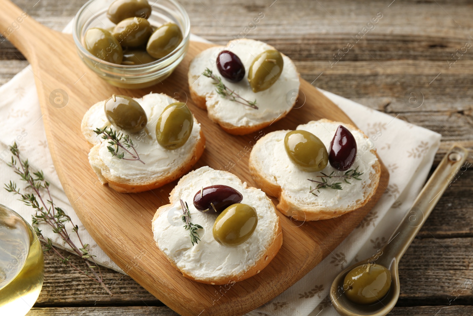 Photo of Delicious sandwiches with marinated olives, cream cheese and thyme on wooden table, above view