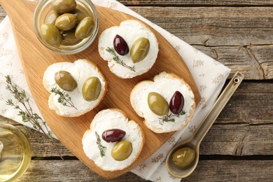 Photo of Delicious sandwiches with marinated olives, cream cheese and thyme on wooden table, flat lay