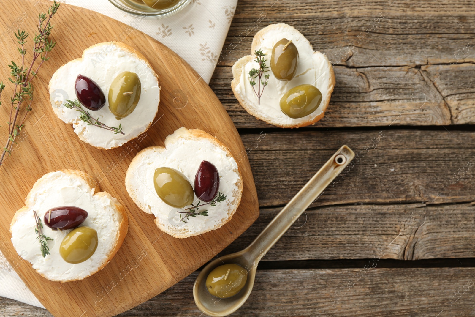 Photo of Delicious sandwiches with marinated olives, cream cheese and thyme on wooden table, flat lay. Space for text