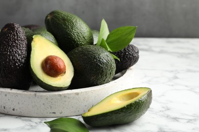 Photo of Whole and cut avocados on white marble table against grey background, closeup. Space for text