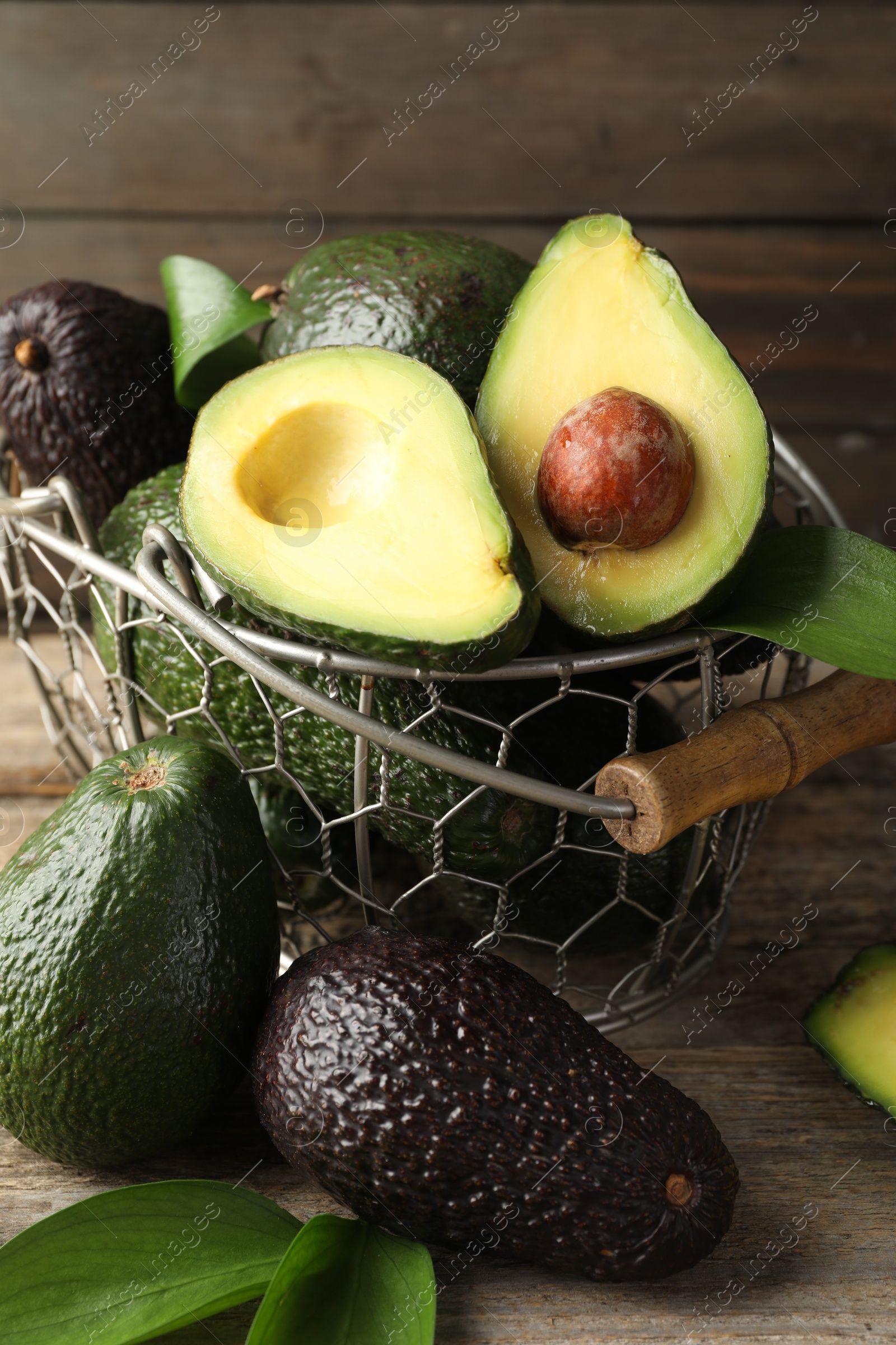 Photo of Whole and cut avocados on wooden table, closeup