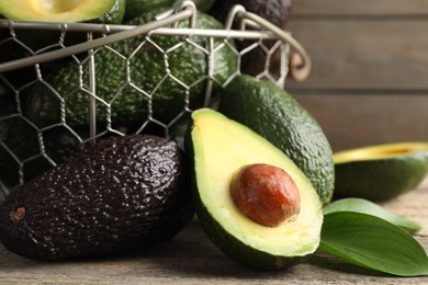 Photo of Whole and cut avocados on wooden table, closeup