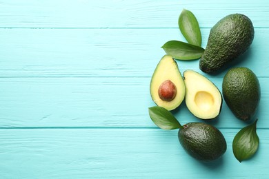 Photo of Whole and cut avocados on light blue wooden table, flat lay. Space for text