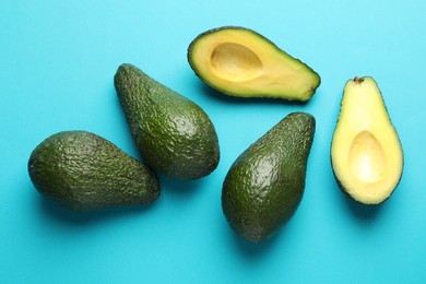 Photo of Whole and cut avocados on light blue background, flat lay