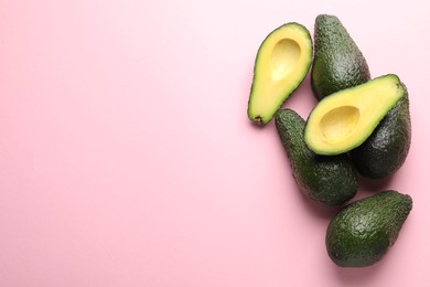 Photo of Whole and cut avocados on pink background, flat lay. Space for text