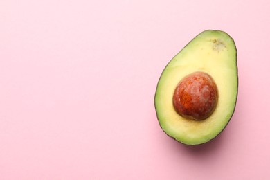 Photo of Half of fresh avocado on pink background, top view. Space for text