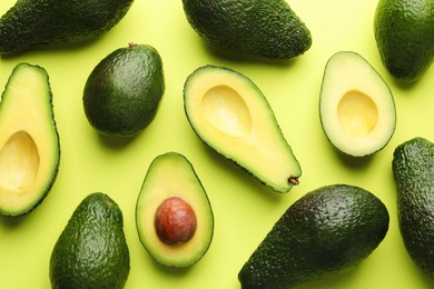 Photo of Whole and cut avocados on light green background, flat lay